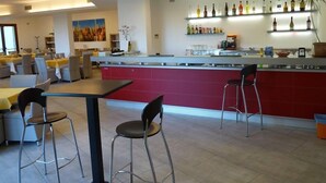 En moderne restaurant med barområde, siddepladser og et udvalg af flasker bag baren.