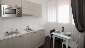 Et moderne køkken med indbygget mikroovn, vask og spiseområde med et bord dækket til to.