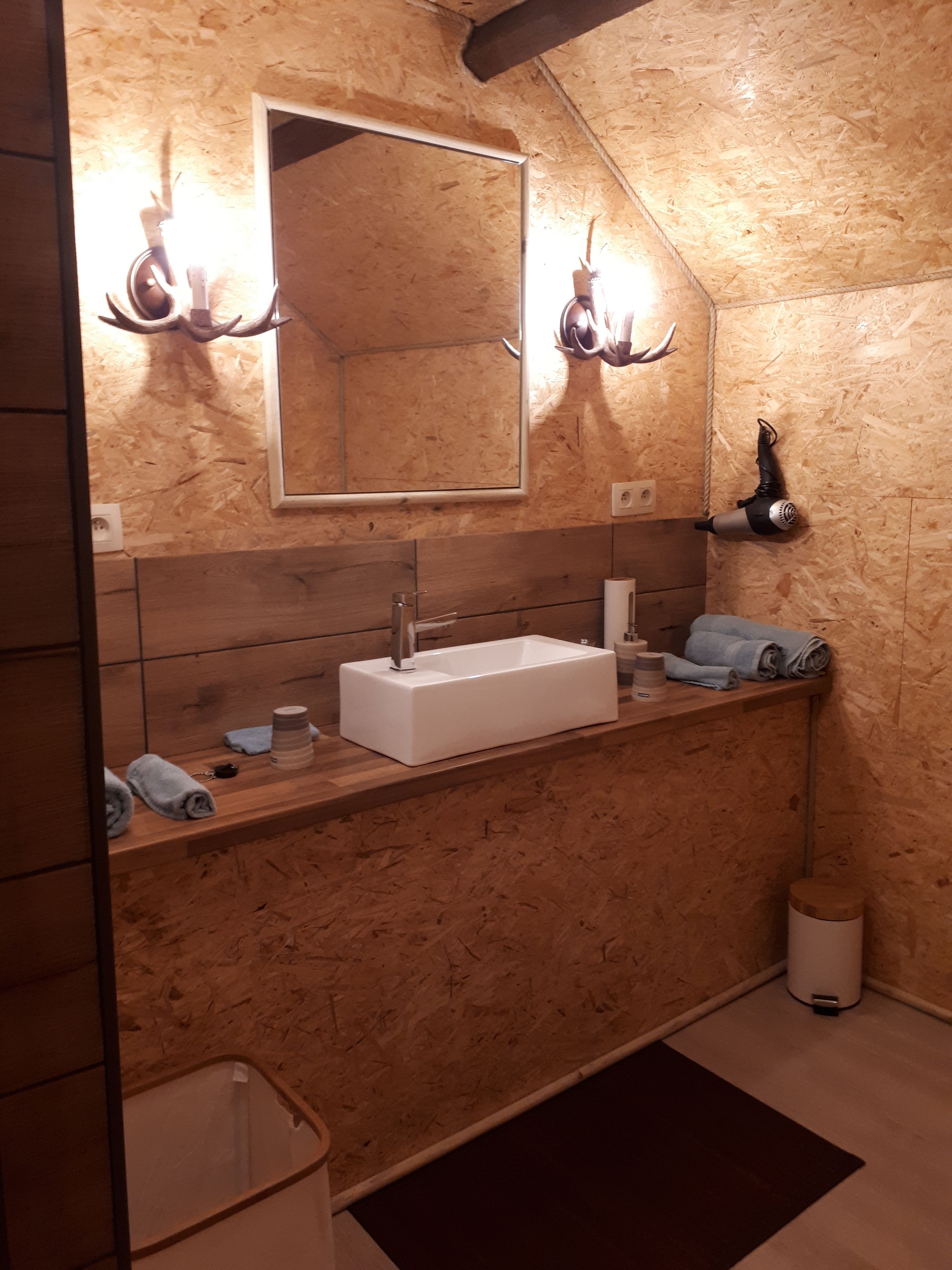 Une salle de bain avec un meuble-lavabo en bois, un grand miroir et un porte-serviettes.