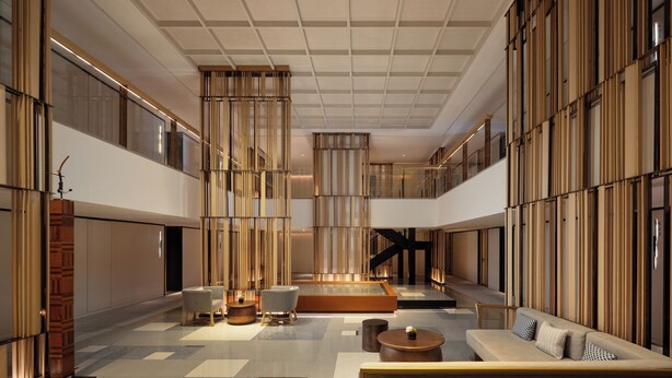 A spacious lobby with a central seating area, a staircase, and a large window wall.