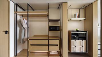 Un dormitorio moderno y compacto con armario empotrado, mesita de noche y una pequeña estantería con libros.
