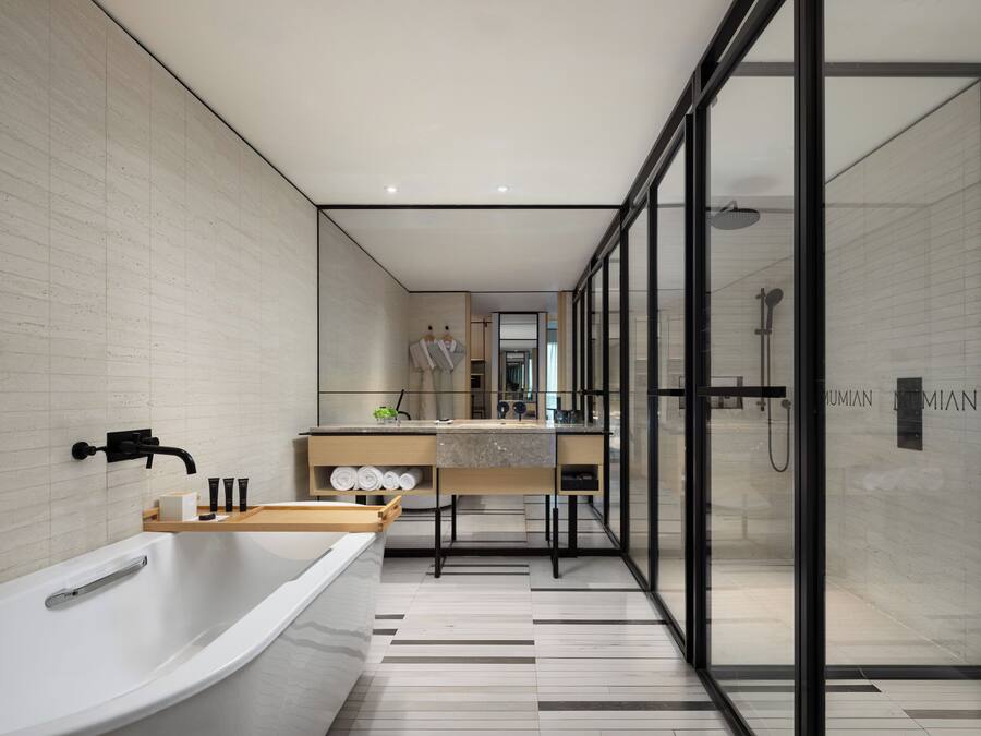Une salle de bain moderne avec une baignoire sur pieds, une douche à l’italienne et un meuble-lavabo avec un miroir.