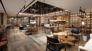 A modern library with wooden floors, multiple seating areas, and a variety of bookshelves.