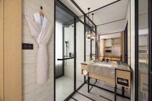 A modern bathroom with a glass shower enclosure, a vanity with a marble countertop, and a large mirror.