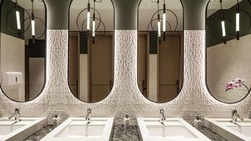 A modern bathroom with four sinks, each with a marble countertop and a mirror above.