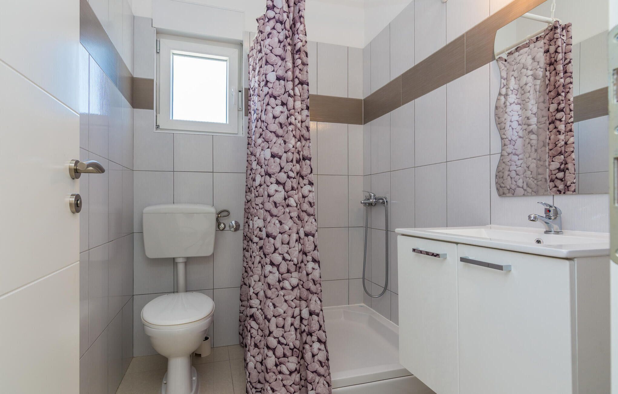 A bathroom with a toilet, shower, and sink.