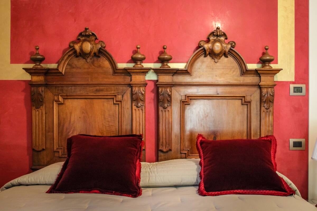A bed with a wooden headboard, two red pillows, and a white bedspread.