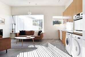 A modern living room with a sofa, coffee table, and washing machine in a compact space. - Nes Residence (Seltjarnarnes)
