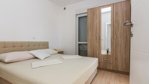 Quarto com cama grande, guarda-roupa de madeira e janela com persianas.