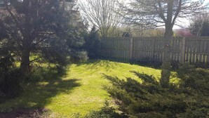 Een gazon met een houten omheining en bomen.
