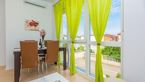 A room with a dining table, chairs, a vase with flowers, and a window with curtains. - Gorgeous apartment in Vir with swimming pool (Vir)