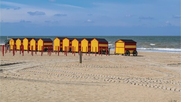 Eine Reihe von Strandkörben mit Strand und Meer im Hintergrund.