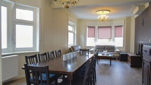 Ein geräumiger Essbereich mit einem langen Holztisch und Stühlen, einer Couch und einer Chandelier.