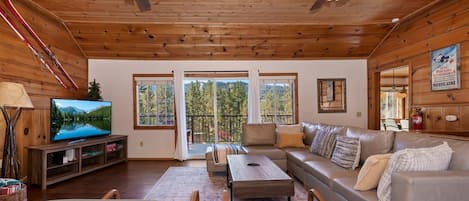 A cozy living room with a wooden ceiling, a television, a sofa, and a fireplace.