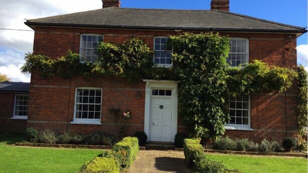 A two-story brick house with a white front door, a small porch, and a garden with neatly trimmed hedges. - Waldegrave farm (Bury St Edmunds)