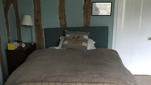 A bedroom with a bed, a nightstand, a lamp, and a door. - Waldegrave farm (Bury St Edmunds)