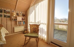 Relax in a peaceful room with a large window, a comfortable rocking chair, and a bookshelf filled with books.