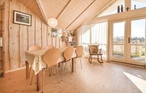 Enjoy meals in this inviting dining area with a wooden table for four, high ceiling, and large window.