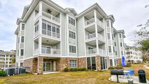 A multi-story residential building with balconies, a brick facade, and a grassy front yard. -  Beautiful, Clean condo, new furniture beds carpet TVs. Lake view, private Wifi  (Myrtle Beach)