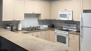A modern kitchen with light-colored cabinets, a central island, a microwave, stove, and a refrigerator. -  Beautiful, Clean condo, new furniture beds carpet TVs. Lake view, private Wifi  (Myrtle Beach)