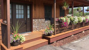 Ein Holzhaus mit einer Steinwand, einer Veranda mit Stufen und einem Holzzaun.