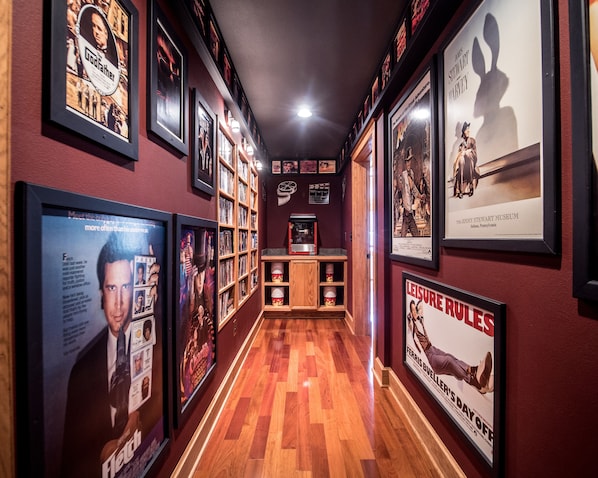 Un pasillo con carteles de películas enmarcados, estantes de madera y piso de madera.