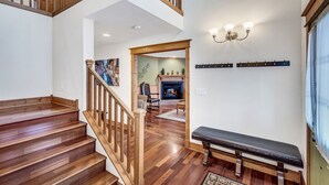 Eine Holztreppe führt zu einem Wohnzimmer mit Kamin, einer Bank und einer Wandleuchte.