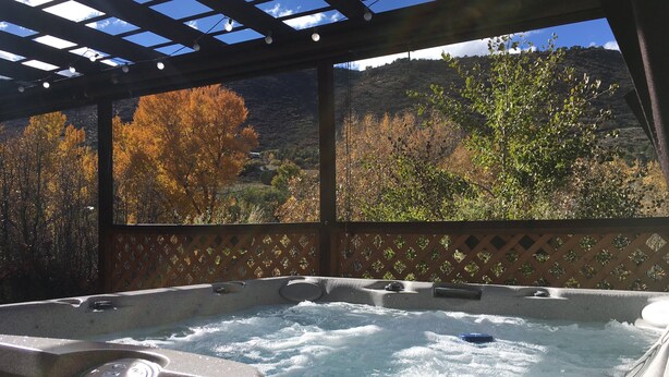 Ein Whirlpool mit Blick auf Herbstbäume und einen Berg im Hintergrund.