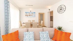 A living room with a sofa, orange and blue patterned pillows, a dining area with a table and chairs, a clock on the wall, and a plant. - Gorgeous home in Kastel Novi with WiFi (Kastel Novi)