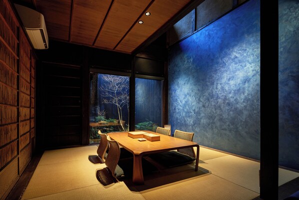 Une pièce de style japonais traditionnel, avec un sol recouvert de tatamis, une petite table en bois et une bibliothèque.
