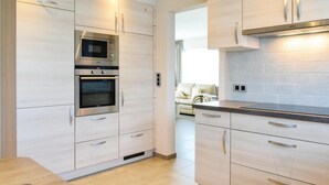 Una cucina moderna con elettrodomestici in acciaio inossidabile, mobili in legno chiaro e un piano di lavoro scuro.