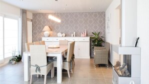 Una cucina moderna con zona pranzo, caratterizzata da un armadietto bianco, un tavolo con sedie, una lampada a sospensione e un camino.