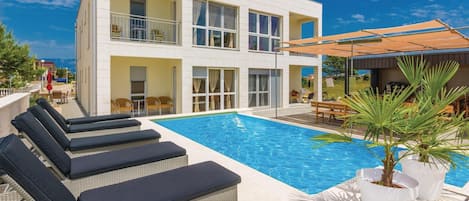 Ein modernes Gebäude mit Schwimmbad, Außenbereich und überdachter Terrasse.