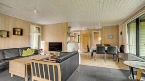 A modern living room with a sofa, coffee table, TV, and dining area with chairs and a table. - 3 bedroom awesome home in Vejers Strand (Vejers Strand)