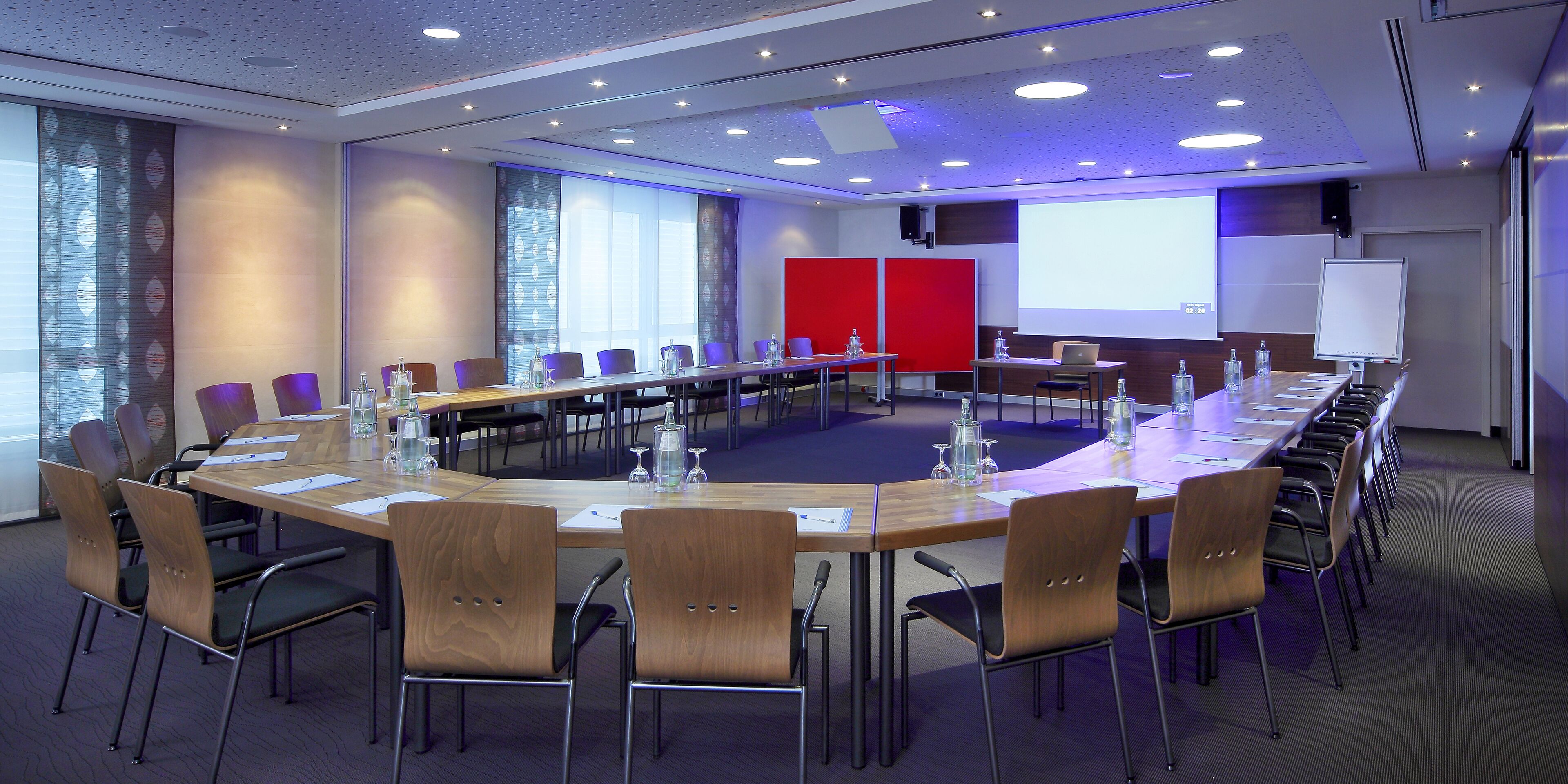 A conference room with a long table, chairs, a projector screen, and a whiteboard.