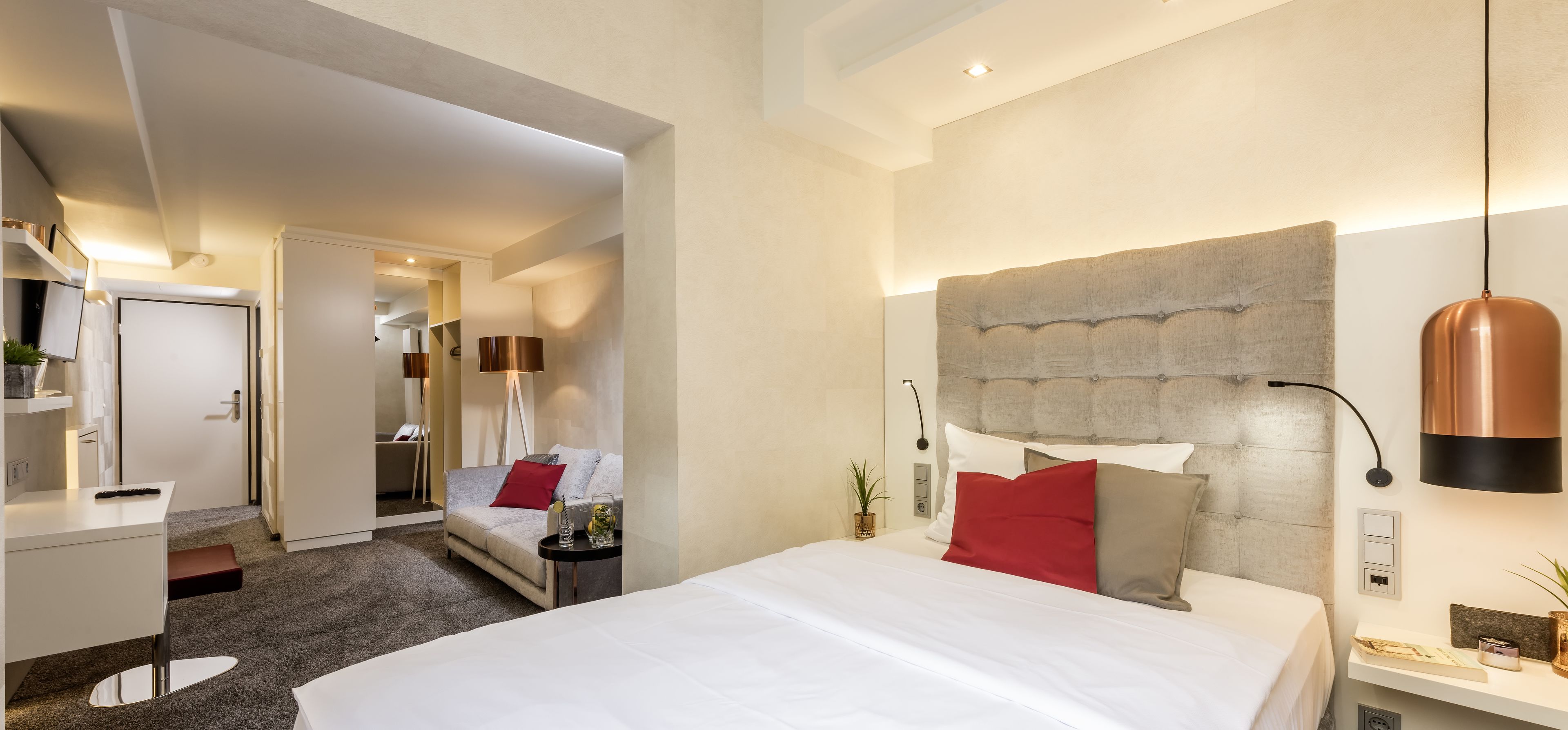 Una habitación de hotel moderna con una cama grande, un escritorio, un sofá y una mesita.