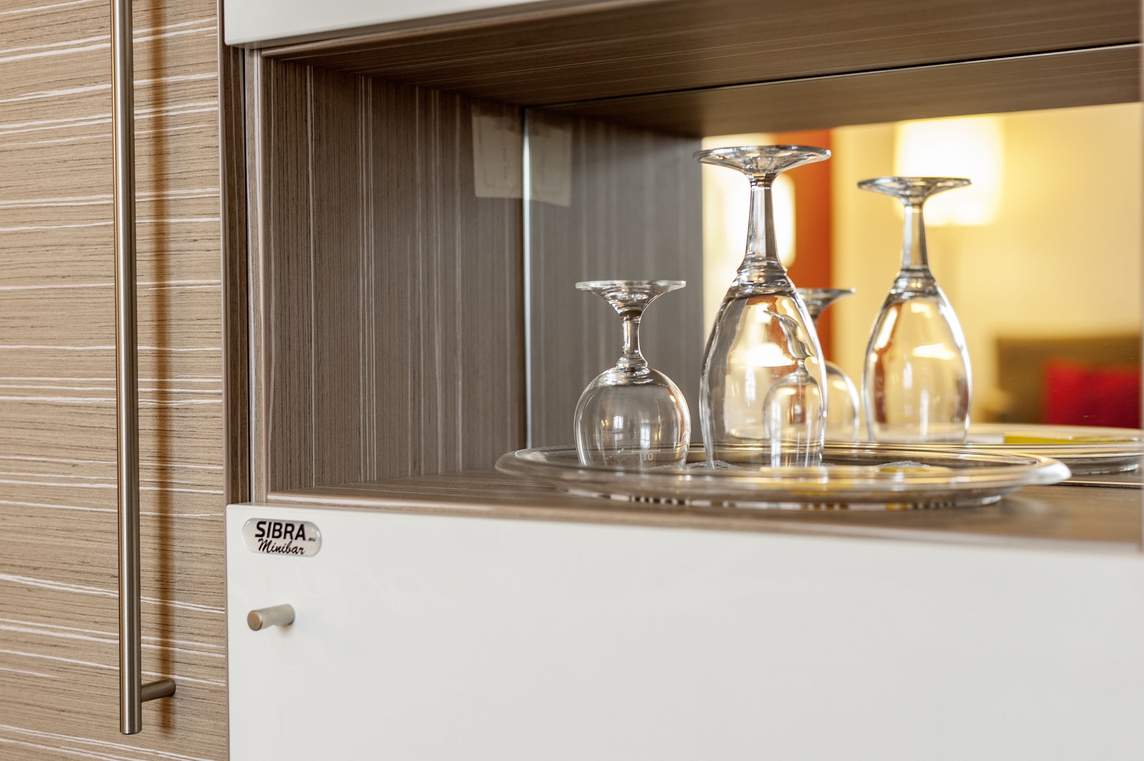 A minibar with a glass wine decanter and a wine glass.