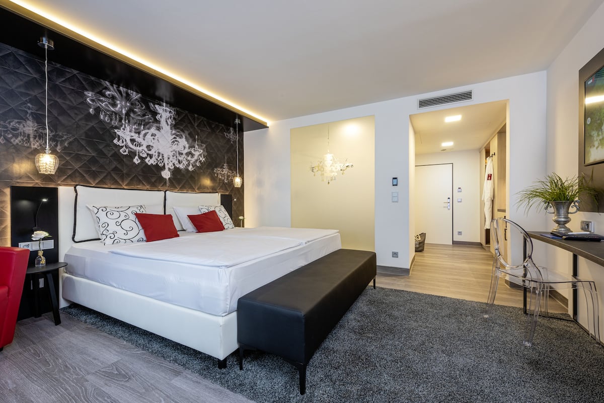 Um quarto moderno com uma cama grande, um banco, uma escrivaninha e uma cadeira.