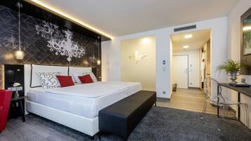 A modern bedroom with a large bed, a bench, a desk, and a chair.