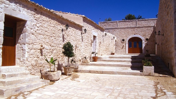 A stone courtyard with steps leading to a building with a wooden door. - Agriturismo Al Casale (Ragusa)