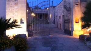 A stone gate with a metal fence, leading to a building with a stone facade. - Agriturismo Al Casale (Ragusa)