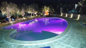 A swimming pool with a curved edge and a fountain feature. - Agriturismo Al Casale (Ragusa)