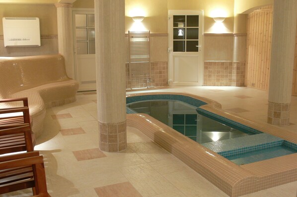 A spa area with a hot tub, seating, and a tiled floor.