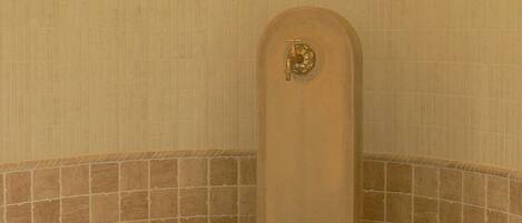 A corner bathroom with a wooden toilet, tiled walls, and a tiled floor.