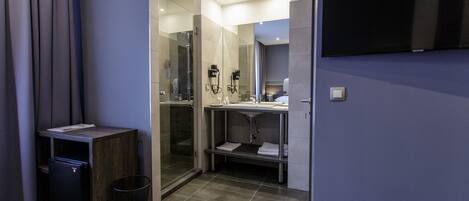 A modern bathroom with a glass shower, a sink, and a toilet.