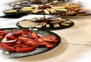 Un bufé con diversos alimentos, como tomates en rodajas, queso y productos de pastelería.