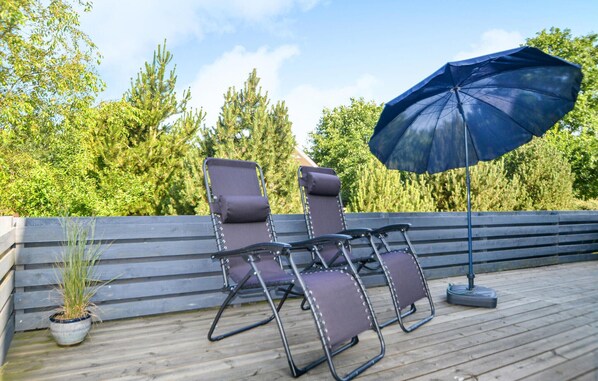 A deck with two reclining chairs and a blue umbrella. - 1 bedroom lovely home in Hovborg (Hovborg)