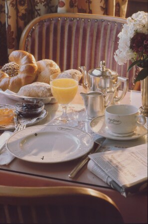 A breakfast setting with croissants, orange juice, and a teapot on a table. - Unser kleines Hotel (Laubach)