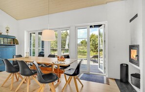Un comedor con una mesa de madera, sillas negras y un ventanal grande.