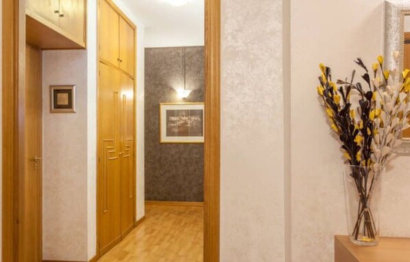 A hallway with wooden doors, a framed picture on the wall, and a vase with flowers on a table. - Kosher Bed&Breakfast La Casa di Eva (Rome)
